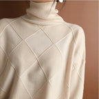 Eine Frau trägt einen beige Rollkragenpullover mit brauner Tasche