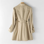 Rückansicht eines khakifarbenen Trenchcoats, der auf einem Kleiderbügel hängt, mit taillierter Taille und Knopfdetails an den Ärmeln.