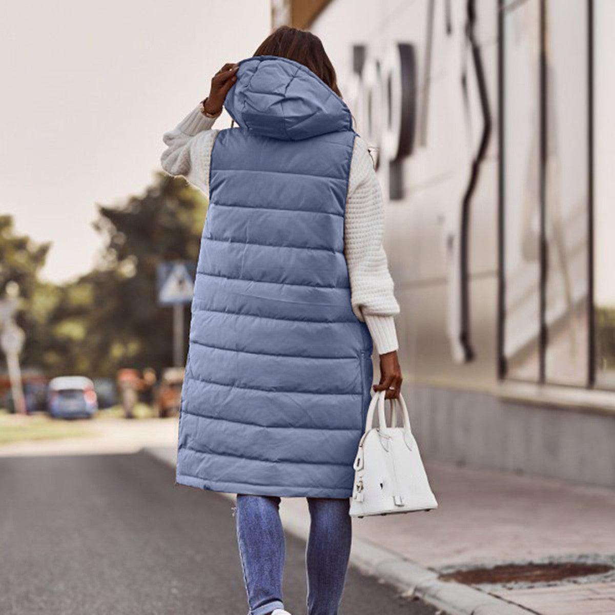 Rückbild einer Frau mit einem langen marinR&Blauen Bodywarmer mit Kapuze