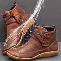Ein paar braun orthopädische stiefel mit wasserspritzern darum herum
